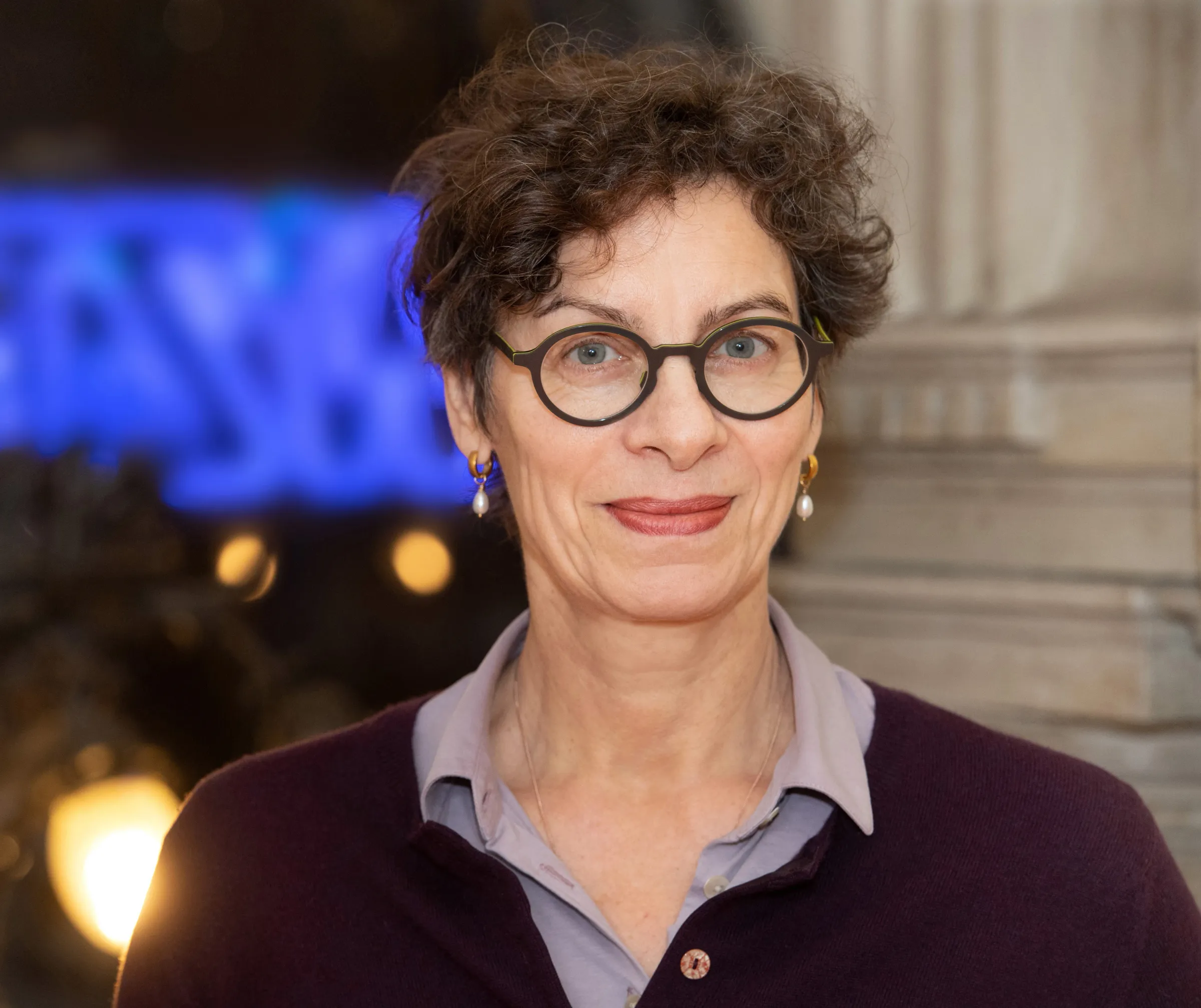 Portrait einer Frau mit lockigem Haar und Brille